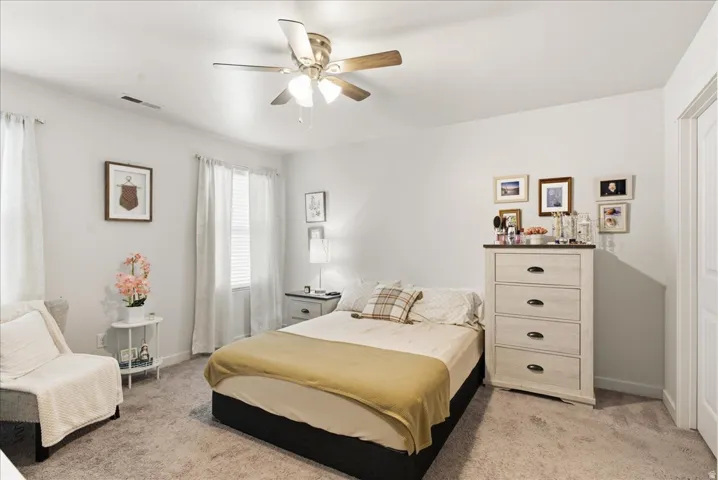 Ceiling fan with light fixture, carpeted flooring, window with blinds, and a white interior door