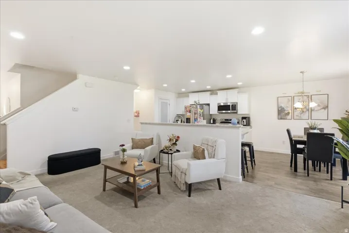 Open-concept living space featuring recessed lighting, a carpeted living area, and wood-finish flooring in the dining area