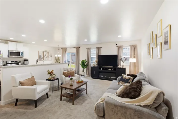 Open-concept living space featuring recessed lighting, a built-in electric fireplace, and light wood-finish flooring