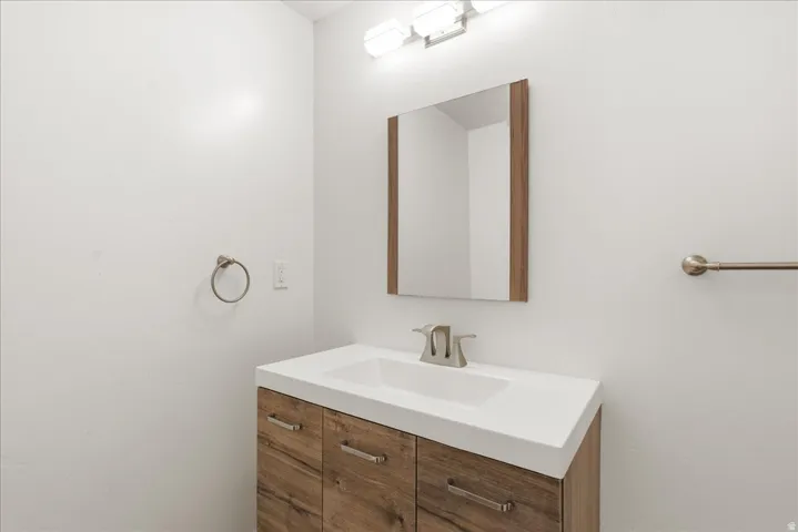Wood-finish vanity with integrated sink, brushed nickel faucet, and an overhead light fixture