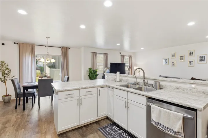 Kitchen featuring white cabinetry, light-toned countertops, a stainless steel sink, and wood-finish flooring