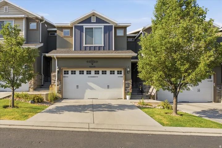 Multi-level facade with stone accents, an attached two-car garage, concrete driveway, and front landscaping