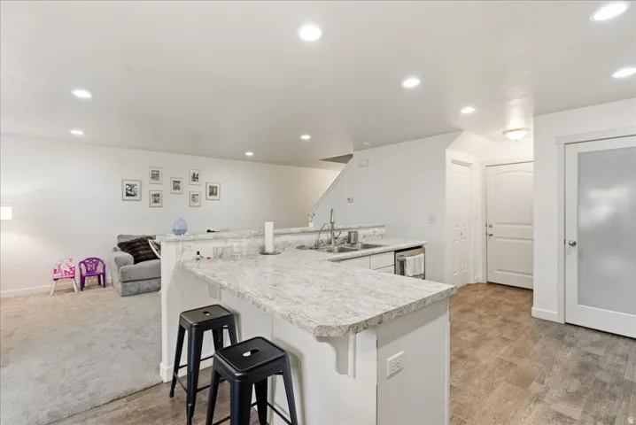 Kitchen island with a light-toned countertop, wood-finish flooring, recessed lighting, and a white paneled door