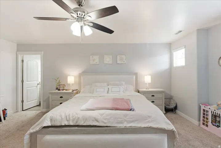 Ceiling fan with light fixture, window with blinds, paneled interior door, and carpeted flooring