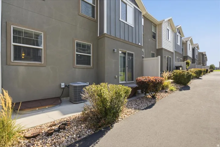 Multi-level townhouse exterior featuring stucco and horizontal siding, with a sliding glass door and private patio area
