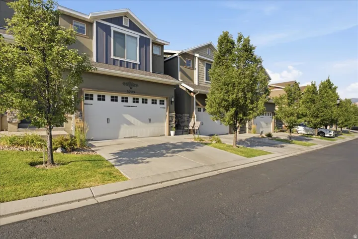 Exterior with stone and siding accents, prominent garage with window inserts, established landscaping, and a concrete driveway
