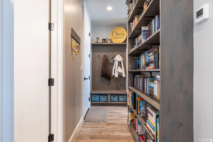 Built-in shelving, wood-finish flooring, recessed lighting, and a built-in bench with coat hooks