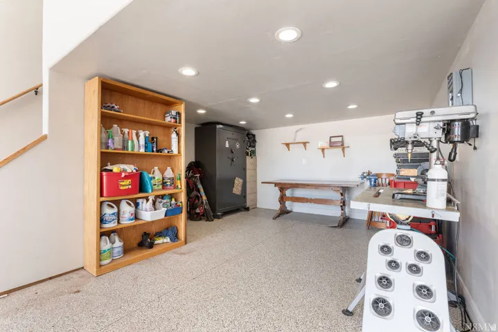 Recessed lighting, wood-finish flooring, staircase with wood handrail, built-in shelving, two wall-mounted wood shelves
