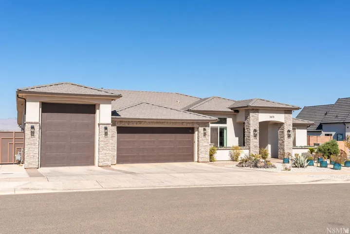 Stucco exterior with stone accents, a multi-car garage, and a covered entry