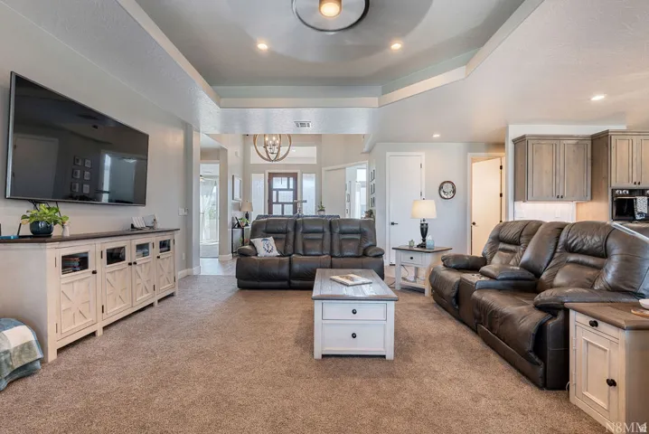 Tray ceiling with recessed lighting, exposed beam accent, built-in cabinetry, and wood-finish flooring