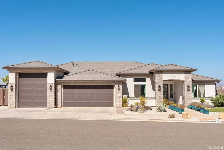 Stucco exterior with stone accents, a multi-car garage, and a covered entry
