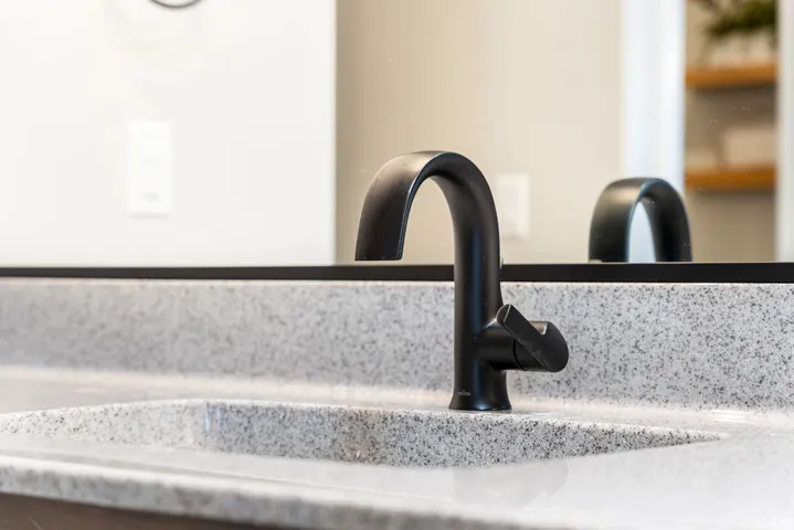 Integrated sink with a speckled countertop and a matte black gooseneck faucet