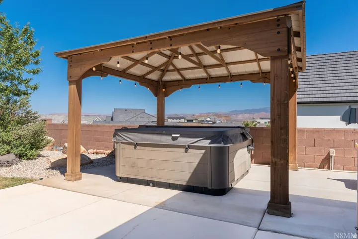 Outdoor pergola with string lighting and an integrated spa