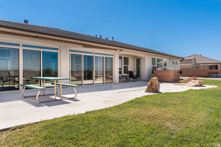 Expansive concrete patio with multiple sliding glass doors, a built-in block planter, and an integrated stone feature
