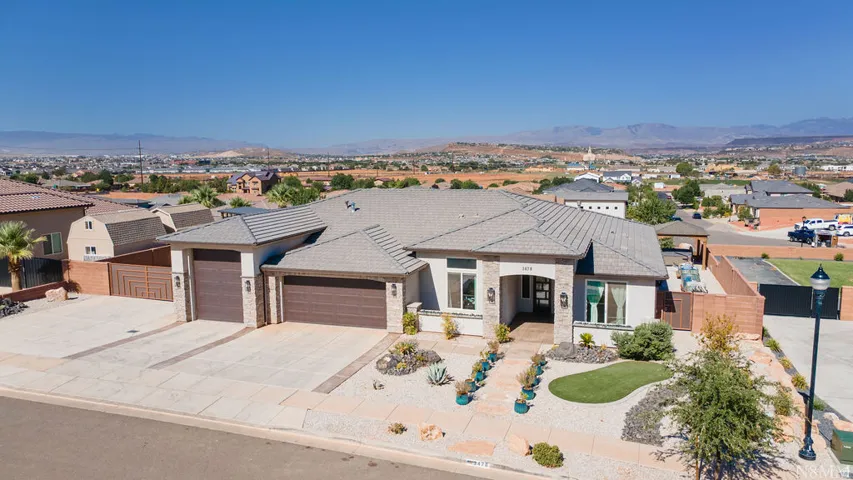 Single-story residence featuring a tile roof, stone façade accents, a two-car garage, and desert-adapted landscaping