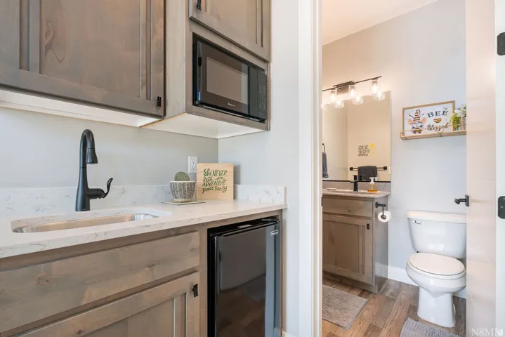 Built-in cabinetry with a sink, black faucet, microwave, and beverage refrigerator