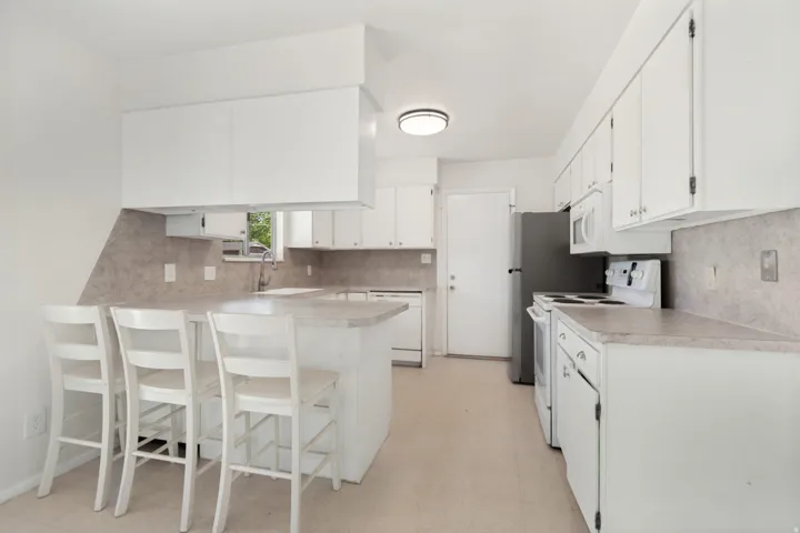 Kitchen featuring white cabinetry, gray countertops, a built-in breakfast bar, and a single basin sink with a chrome faucet