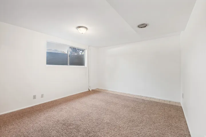 Carpeted flooring, white walls, and a window with a horizontal blind
