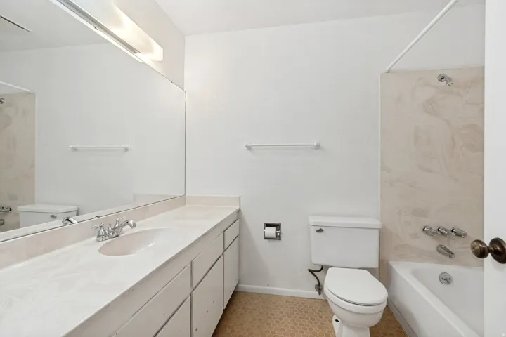 Spa-inspired bathroom featuring a long vanity with dual sinks, marble-finish countertops, and polished chrome fixtures