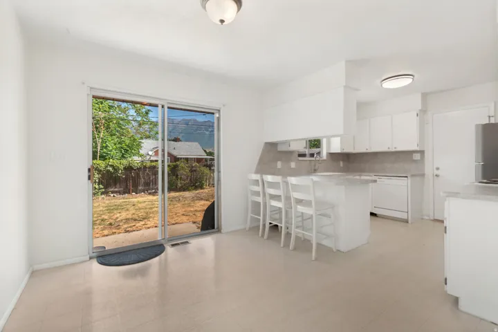 White kitchen cabinetry with a light-toned countertop, a built-in dishwasher, and a sliding glass door