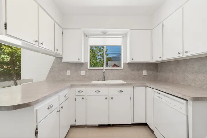 White cabinetry with brushed nickel hardware, laminate countertops, and a white integrated sink with a gooseneck faucet