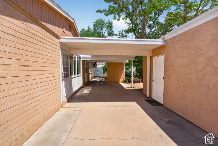 Covered walkway with concrete flooring, stucco exterior, and horizontal panel siding