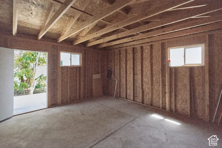 Framed interior structure with exposed ceiling joists, two windows, and an open doorway