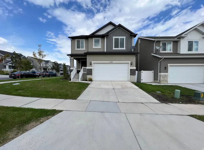 Two-story residence featuring a two-car garage, concrete driveway, and a covered front porch