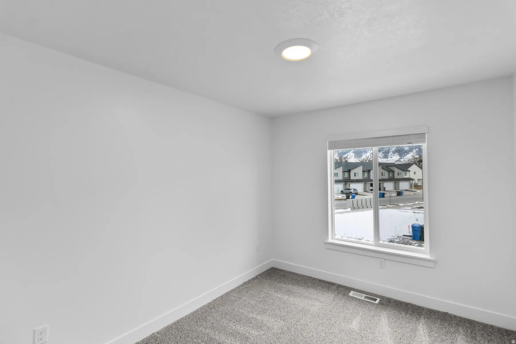 Bright secondary bedroom with carpet flooring, recessed ceiling lighting, and large window framing natural light and neighborhood views