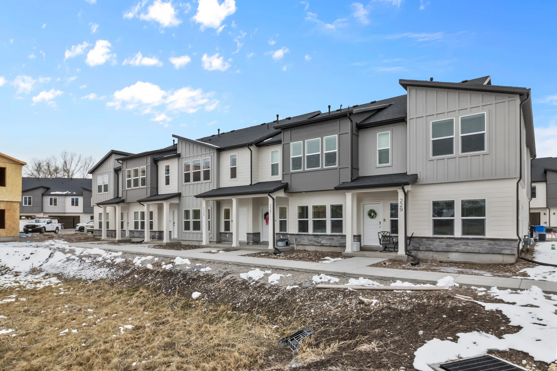 Contemporary townhomes featuring multi-tone siding, stone accents, and covered entryways