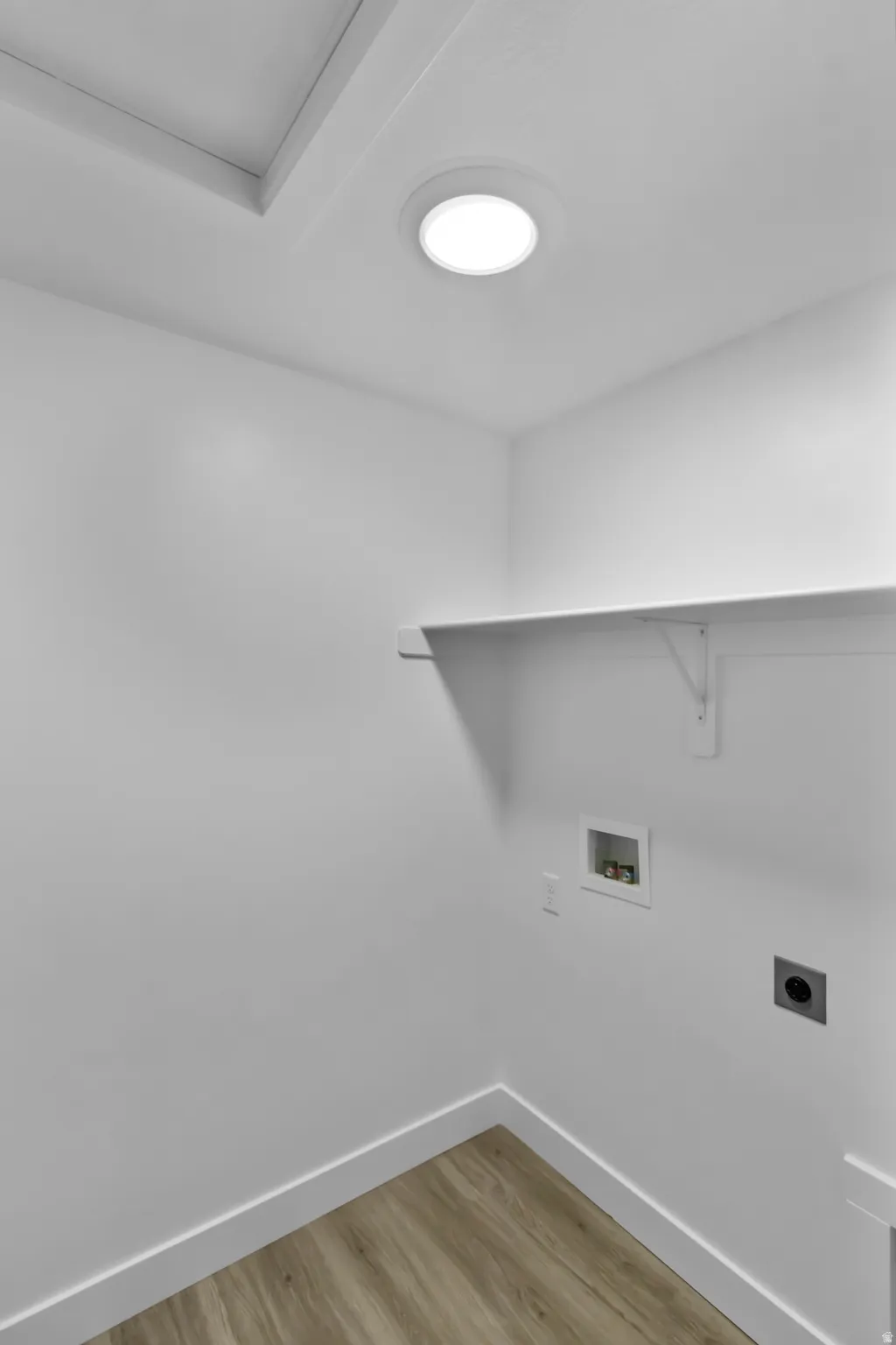 Laundry area featuring wood-finish flooring, a white wall shelf, and recessed lighting