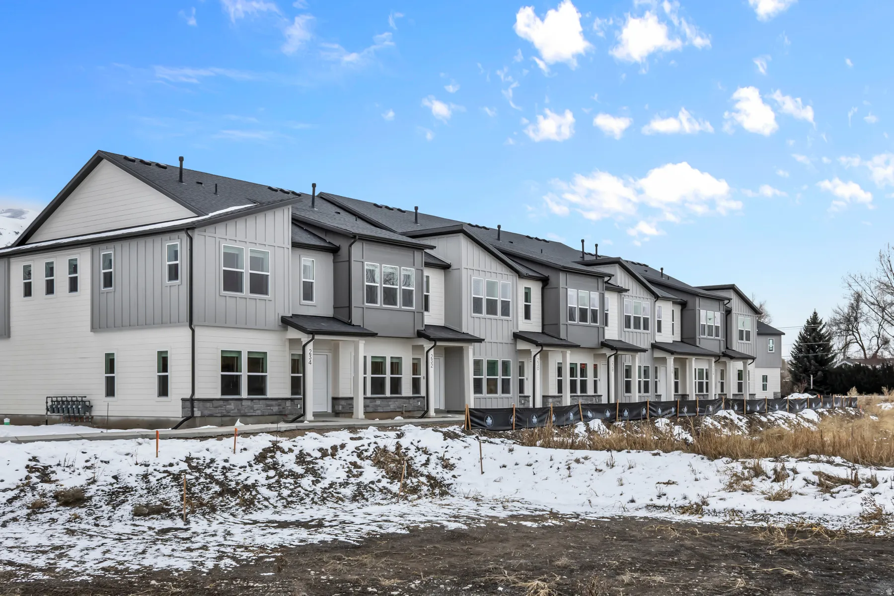 Modern townhome-style residences featuring clean-lined architectural design with gabled rooflines, metal roof accents, and composite or fiber cement siding in neutral tones