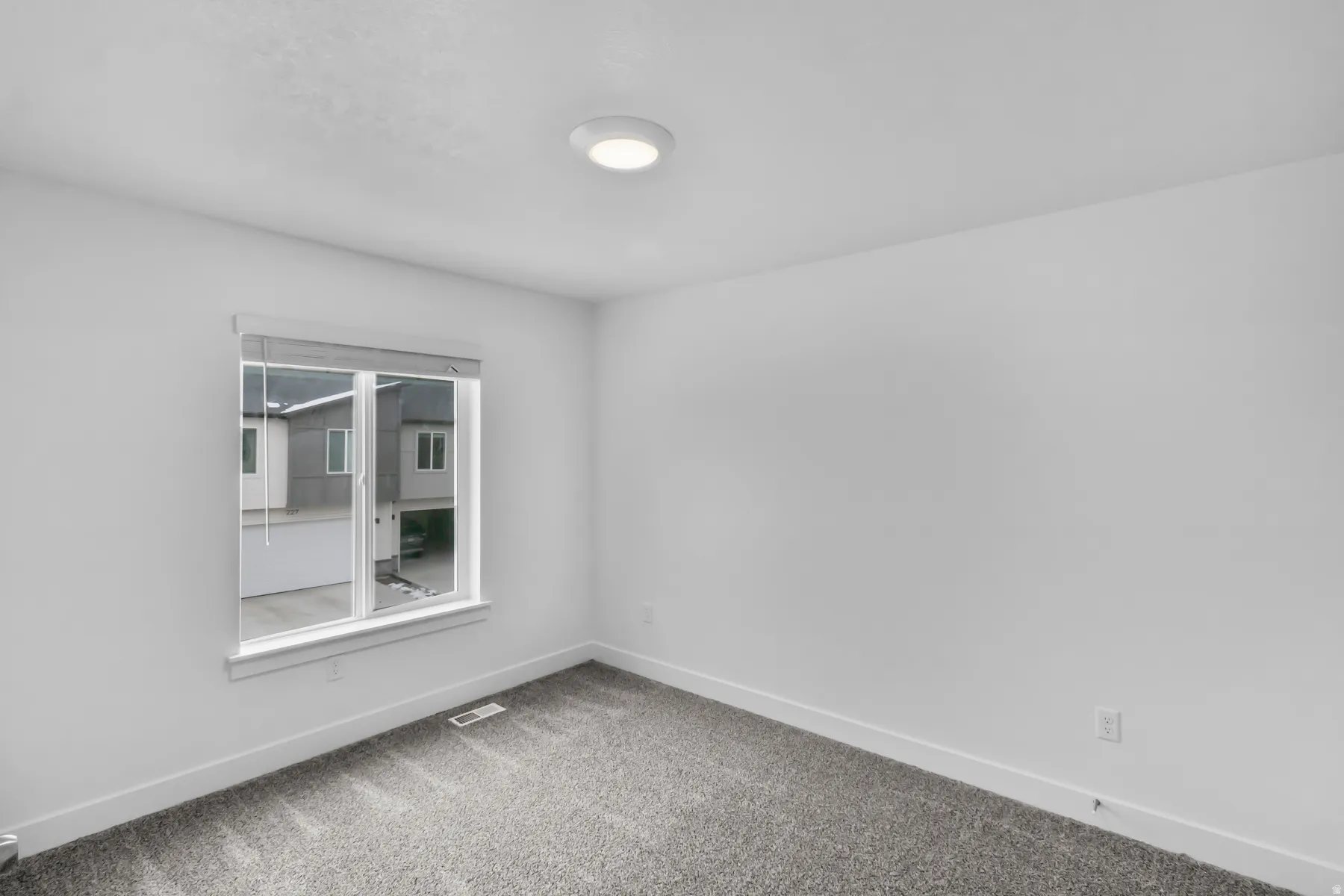 Recessed lighting, neutral wall finishes, gray carpeting, and a double-pane window