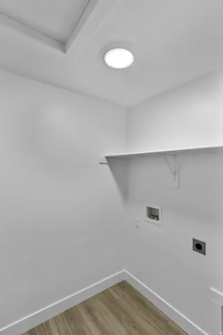 Laundry area featuring wood-finish flooring, a white wall shelf, and recessed lighting