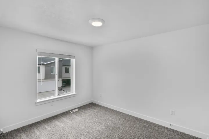 Recessed lighting, neutral wall finishes, gray carpeting, and a double-pane window