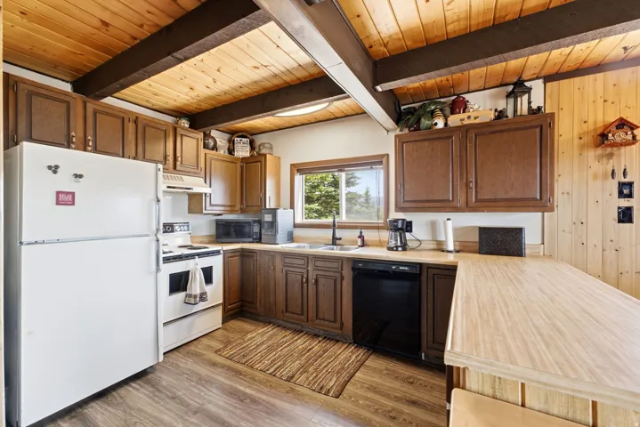 Warm and functional kitchen featuring wood cabinetry, wood-finish flooring, and exposed beam ceiling details