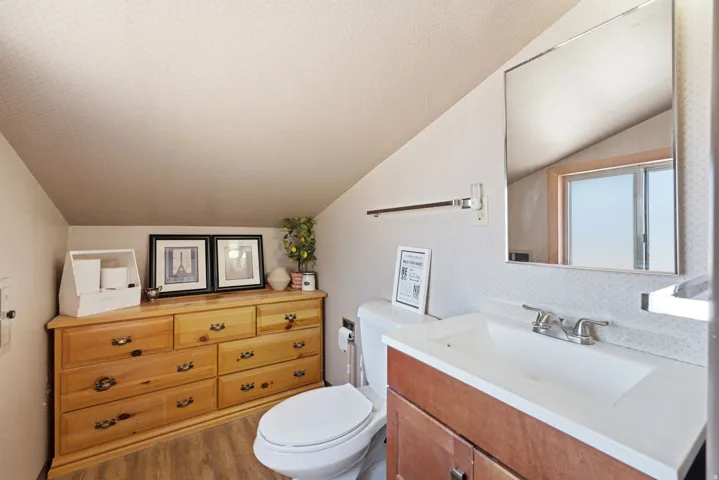 Spa-inspired primary bathroom featuring a wood-finish vanity with dual sinks, white quartz countertop, and a large frameless mirror with integrated lighting