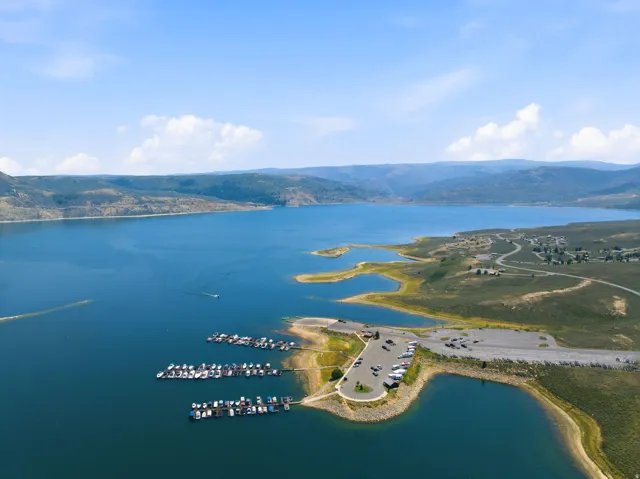 Expansive body of water with a distinct shoreline, a marina with multiple boat slips, and a large parking area