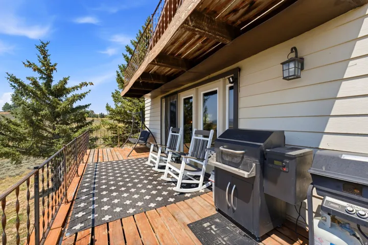 Expansive wood deck with metal railing, exterior wall light fixture, and natural landscape