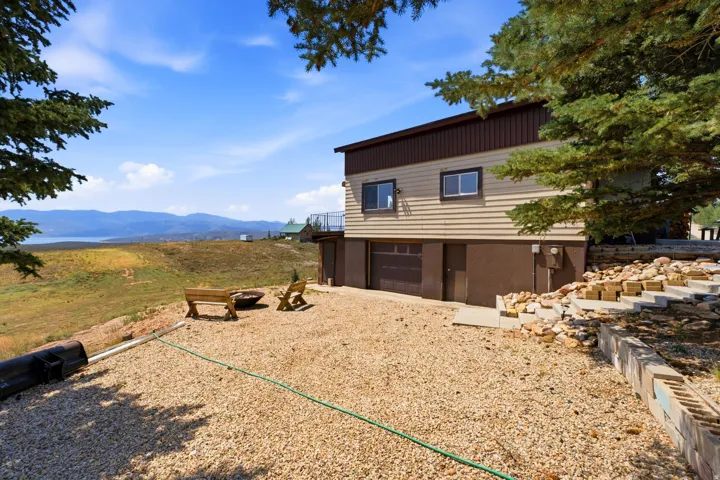 Split-level residence featuring a lower-level garage, upper-level balcony, and a gravel-covered outdoor area