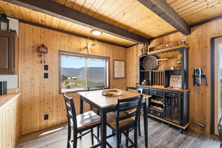 Warm wood-paneled dining space with exposed beam ceiling and recessed lighting