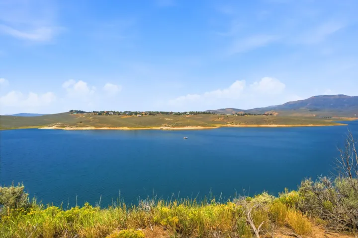 Expansive water body with surrounding natural hillsides and distant residential structures