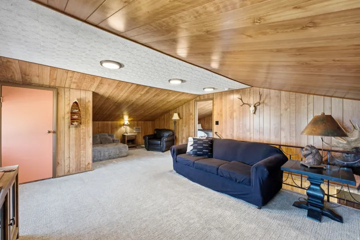 Expansive finished basement showcasing warm wood-finish ceiling and paneling, recessed lighting, neutral carpeting throughout, and multiple functional zones with ample square footage for recreation and storage