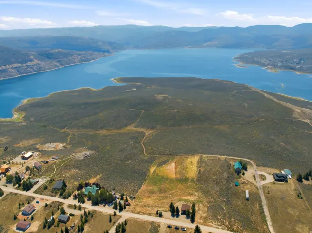 Expansive water body, mountainous terrain, scattered residential properties, arid vegetation, and winding roads