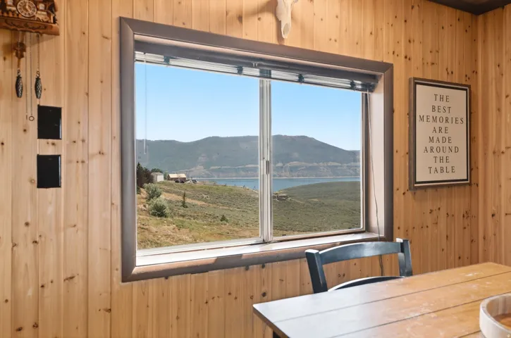 Bright interior space featuring knotty pine wood-finish walls and ceiling, large dual-pane windows with contemporary framing, and expansive sightlines toward distant mountains and waterfront landscape