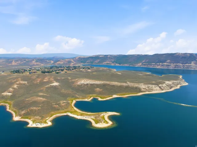 Expansive water body with surrounding land, distant village, and mountainous terrain