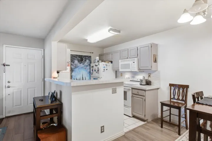 Kitchen with white appliances, grey cabinetry, and white countertops