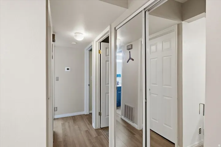Recessed lighting, wood-finish flooring, white panel doors, and mirrored closet doors