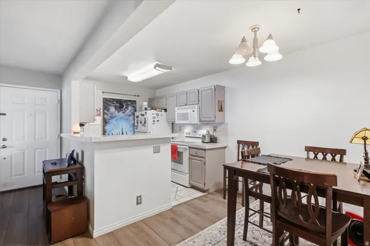 Kitchen featuring light gray cabinetry, white appliances, and a breakfast bar with a light-colored countertop