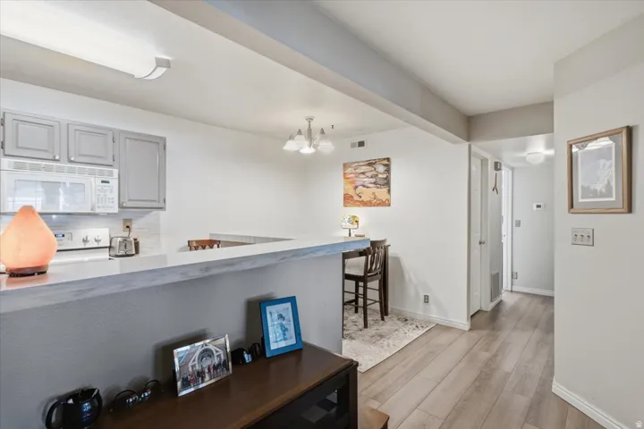 Kitchen featuring grey cabinetry, white microwave, and a white tile backsplash